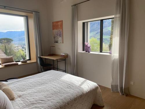 1 Schlafzimmer mit einem Bett, einem Schreibtisch und 2 Fenstern in der Unterkunft Villa Tschaupp in Dorf Tirol