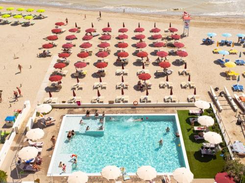 einen Blick über den Pool und den Strand mit Sonnenschirmen in der Unterkunft Hotel Classic in Lido di Savio
