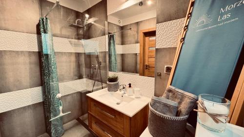 een badkamer met een wastafel en een douche met een spiegel bij Morze Las Domki nad morzem Rozewie in Rozewie