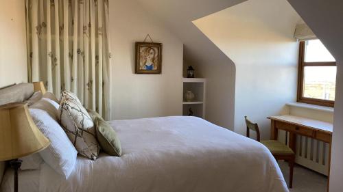 um quarto com uma cama, uma secretária e uma janela em Drop Anchor Guesthouse em Cleggan