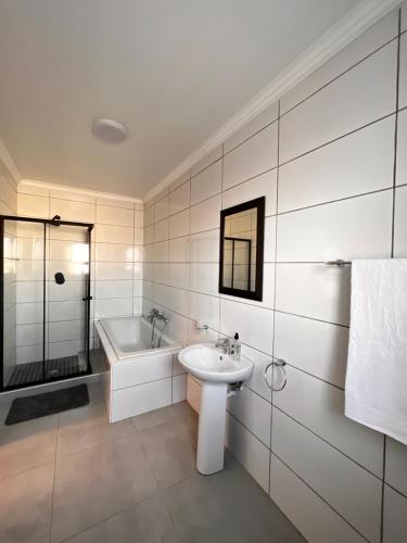 a white bathroom with a sink and a bath tub at 2nd on Strand in Cape Town