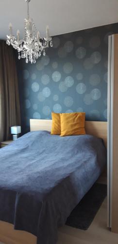 um quarto com uma cama azul e um lustre em GalériusPrémium6 em Siófok