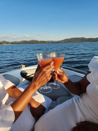 two people holding up drinks on a boat at Le Bamboo Guest House And Boat Cruise in Hartbeespoort