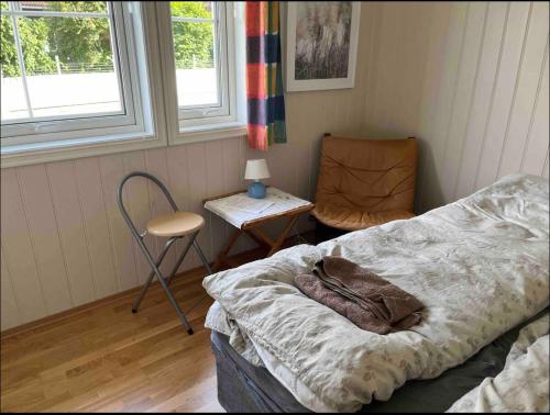 a bedroom with a bed and a chair and a table at Bjørn og Jasmins plass in Lærdalsøyri