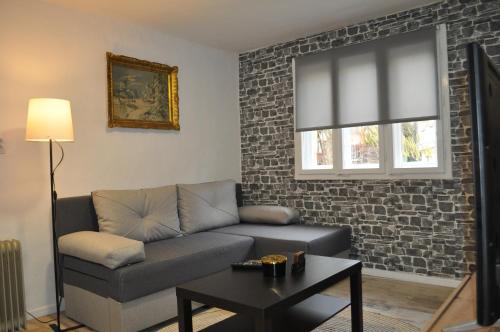 - un salon avec un canapé et un mur en briques dans l'établissement Apartman Kućica - Smederevo, à Smederevo