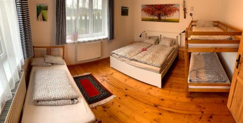 a room with three bunk beds and wooden floors at Chalupa Zlíčko in Vysoká Srbská