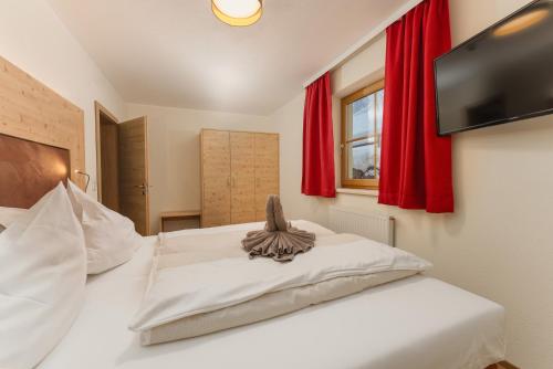 a bedroom with a white bed with red curtains at Berghotel Jaga-Alm in Zell am See