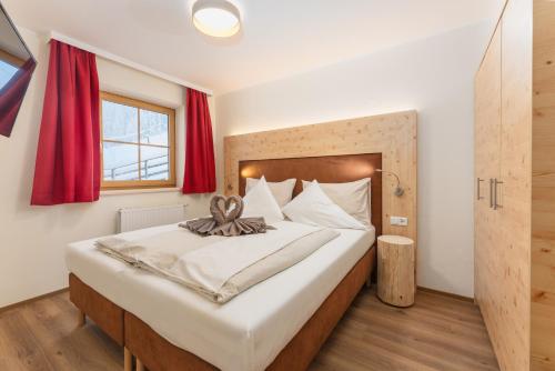 a bedroom with a large bed with red curtains at Berghotel Jaga-Alm in Zell am See