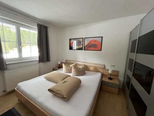 1 dormitorio con 1 cama blanca grande y 2 almohadas en Ferienwohnung Höllrigl, en Sankt Leonhard im Pitztal
