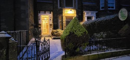 a house with a yellow door and a fence at Ferndene Guest House in Keswick