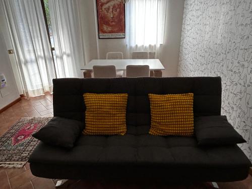 Sofá negro con 2 almohadas amarillas en la sala de estar en Appartamento in centro a Spoleto, en Spoleto