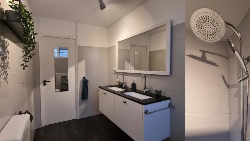 uma casa de banho branca com um lavatório e um espelho em Natuurhuis Boscoso met openhaard en elektr.fietsen em Barchem