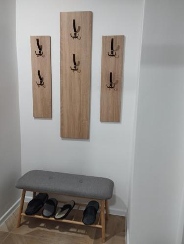 a bench with hooks and shoes on a wall at Apartman Nona in Kupres