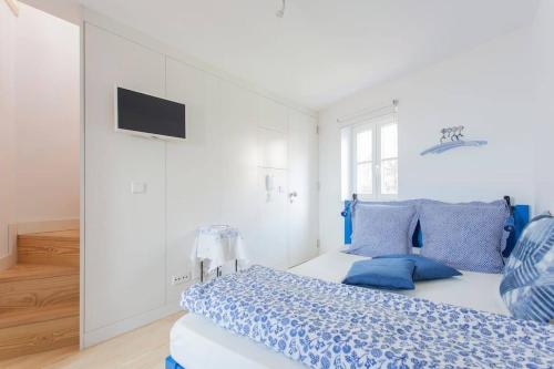um quarto branco com uma cama com almofadas azuis em Sao Vicente II, Eco-penthouse, best view of Lisbon em Lisboa
