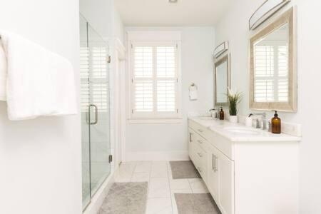 a white bathroom with two sinks and a shower at The Lillian House - Steps to Five Points in Nashville