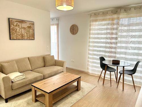 ein Wohnzimmer mit einem Sofa und einem Tisch in der Unterkunft Bel appartement lumineux résidentiel proche de Paris in Ivry-sur-Seine