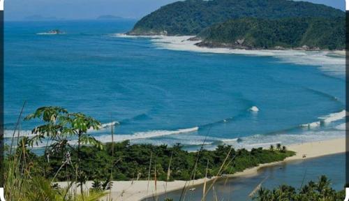 - une vue sur la plage avec des arbres et l'océan dans l'établissement Chales Guarau, à Peruíbe