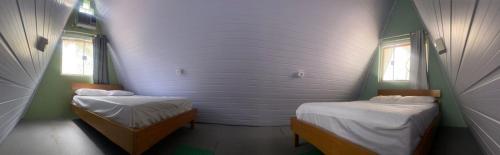 Cette chambre comprend 2 lits et 2 fenêtres. dans l'établissement Chales Guarau, à Peruíbe