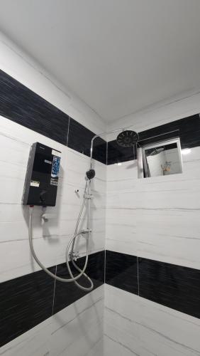 a shower in a bathroom with black and white tiles at DUSUN TOK SYED, ECOTHERAPY VILLAGE in Pendang