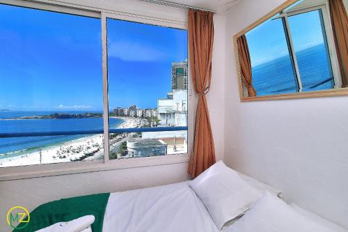 a bedroom with a window with a view of the beach at Oceanfront penthouse with private pool Copacabana in Rio de Janeiro