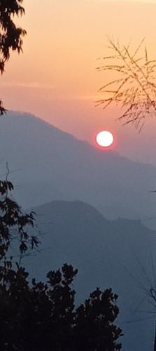 een zonsondergang in de bergen met de zon in de lucht bij Saveen View Ella in Ella
