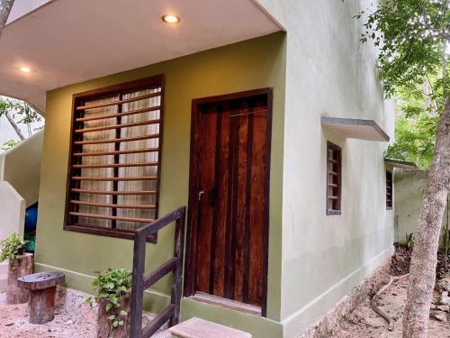 a small house with a wooden door and stairs at Hokhmah Heart Hotel in Puerto Morelos