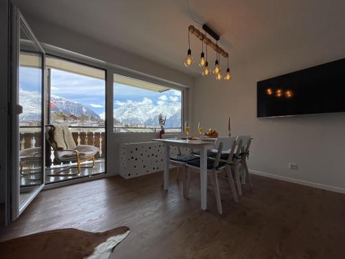 a dining room with a table and a view of mountains at Sunny Alps View: Central Bliss in Grächen