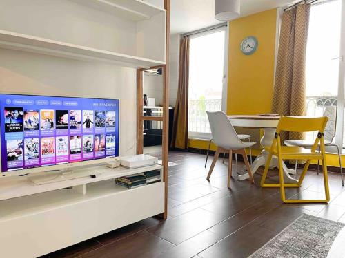 uma sala de estar com uma televisão e uma mesa com cadeiras em Le St Laurent - Ma Cabotte em Chalon-sur-Saône