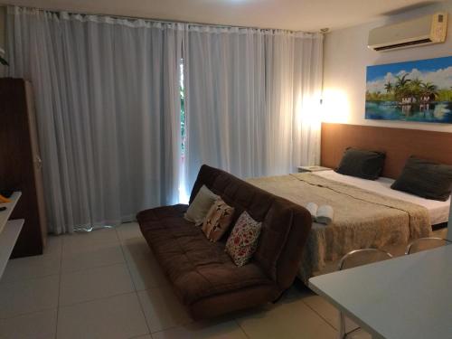 a bedroom with a bed and a couch in front of a window at Vários Apartamentos no villas maceio in Maceió