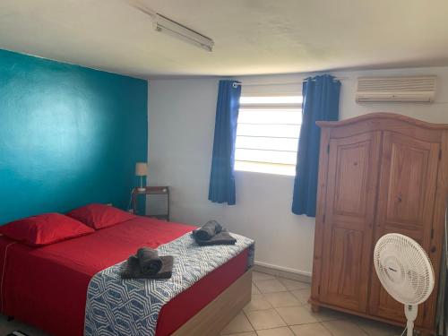 een slaapkamer met een rood bed en een blauwe muur bij F1 BLUE MARINE in Le Marin