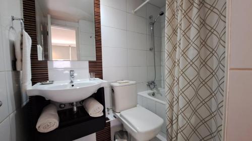 a white bathroom with a sink and a toilet at Brizen Apartments in Santiago