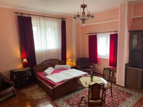 1 dormitorio con cama, mesa y cortinas rojas en Villa Maruška Kladská, en Mariánské Lázně