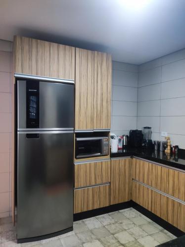 a kitchen with a stainless steel refrigerator and wooden cabinets at Casa para Relaxar in Poá