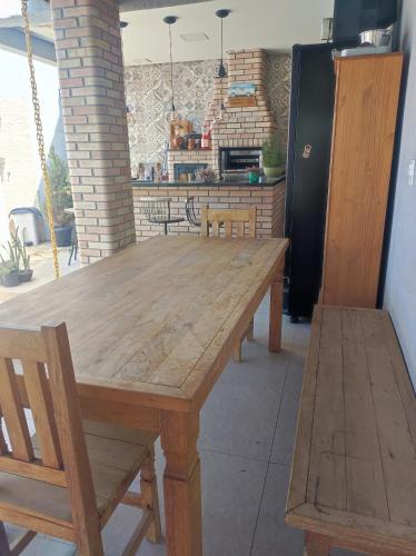 a wooden table with two chairs and a kitchen at Casa para Relaxar in Poá