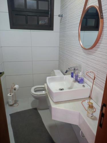 a white bathroom with a sink and a toilet at Casa para Relaxar in Poá