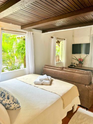 a bedroom with a bed and a couch and a window at Chales do Oliveira in Porto Seguro