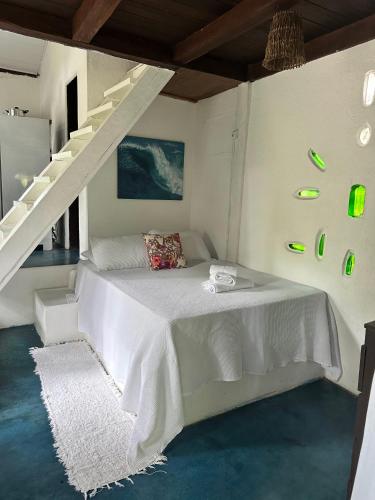 a bedroom with a white bed with a staircase at Chales do Oliveira in Porto Seguro