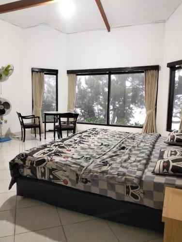 1 dormitorio con cama, mesa y ventanas en Villa sagitarius en Bogor