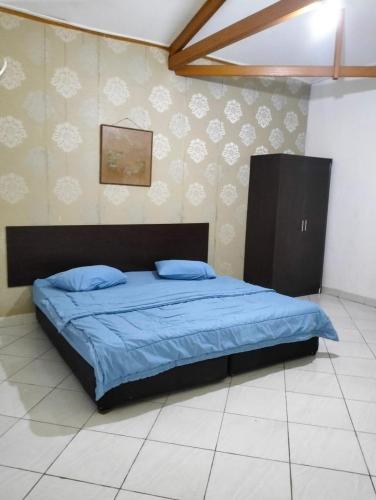 a bedroom with a bed with a blue comforter at Villa sagitarius in Bogor