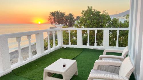 a balcony with chairs and a table and the beach at Wadi shab Beach Resort in Sur