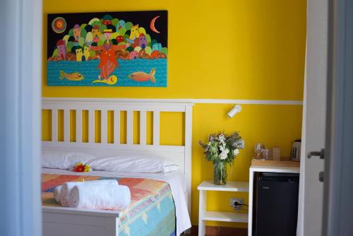 a yellow bedroom with a bed and a painting on the wall at ARIA DI MARE, Manarola - Camere con vista mare! in Manarola