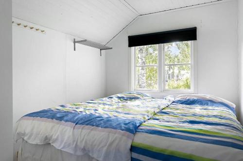 Cama en habitación blanca con ventana en Fritidshus på backstigen 3 i Surahammar, en Surahammar