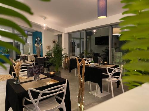 un restaurant avec des tables noires et des chaises blanches dans l'établissement Hotel La Voile, à Bormes-les-Mimosas