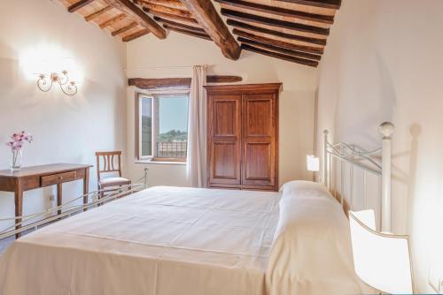 Schlafzimmer mit einem Bett, einem Schreibtisch und einem Fenster in der Unterkunft Antica Grancia Di Quercecchio in Montalcino