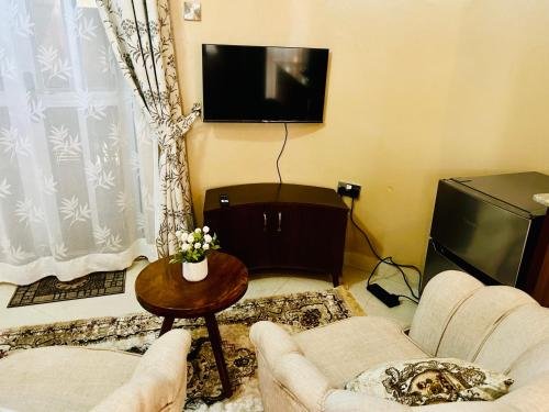 een woonkamer met 2 stoelen en een televisie bij Casa Mia BnB in Kampala