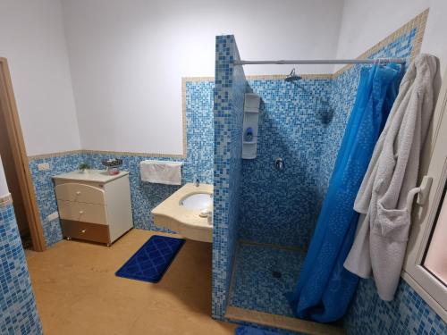 y baño con ducha de azulejos azules y lavamanos. en Villa Serroni, en Mazara del Vallo