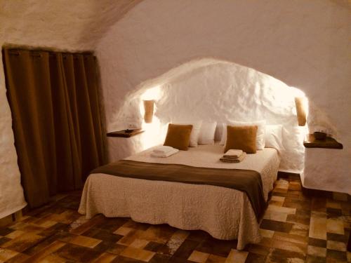 1 dormitorio con 1 cama grande y cabecero blanco en Cueva Aventura, en Benamaurel