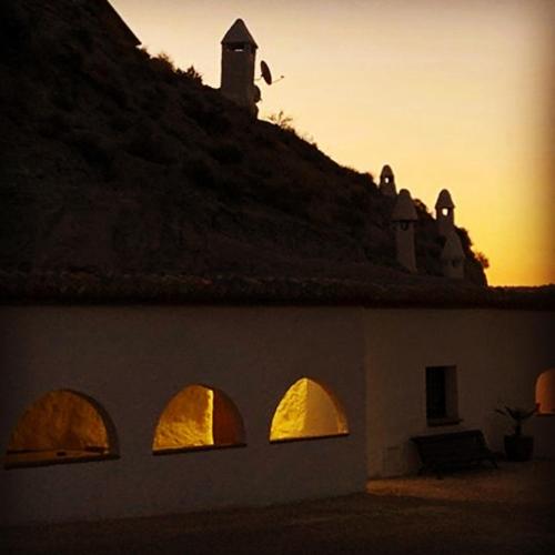 a building with arches and a bird flying over it at Cueva Aventura in Benamaurel