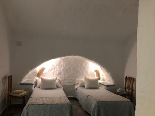 two twin beds in a room with an arch at Cueva Aventura in Benamaurel