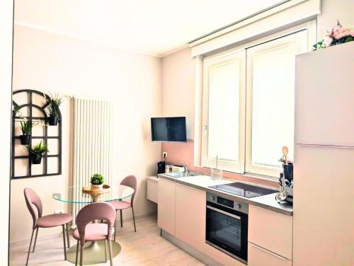 La cuisine est équipée d'une table, de chaises et d'un réfrigérateur. dans l'établissement Maison del Ducato Suite Parmigianino, à Parme